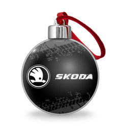 Ёлочный шар Skoda Speed на темном фоне со следами шин: надпись и символ